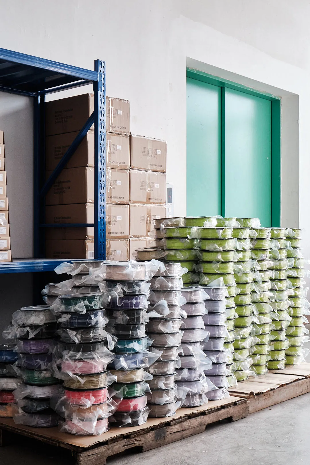 asa bulk filament spools stacked on pallets wrapped in plastic in warehouse storage area