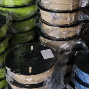stacked 3d printing filament spools vacuum sealed packaging green beige blue colors warehouse storage