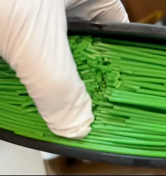 gloved hand holding brittle PLA filament pieces broken into short segments inside a spool
