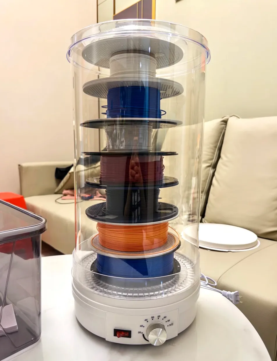 multiple PLA filament spools stacked inside a food dehydrator used for drying 3D printing filament