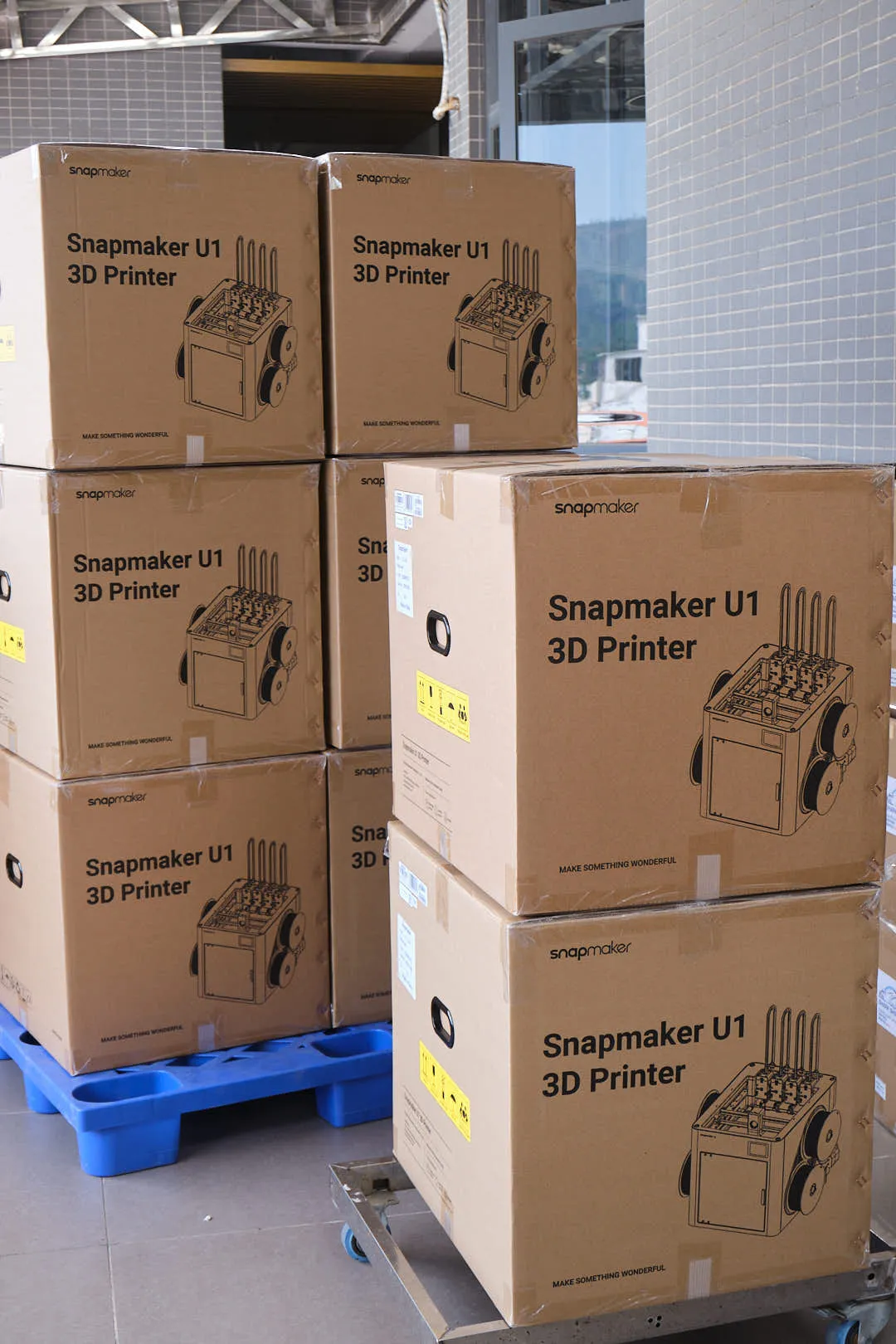 Stacked Snapmaker U1 3D printers in original boxes on pallets for wholesale shipment