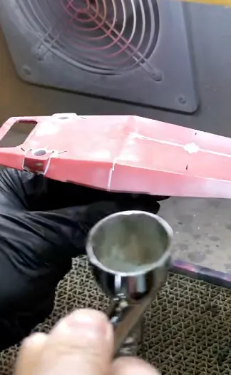 airbrush spraying primer onto PLA 3D printed part inside spray booth